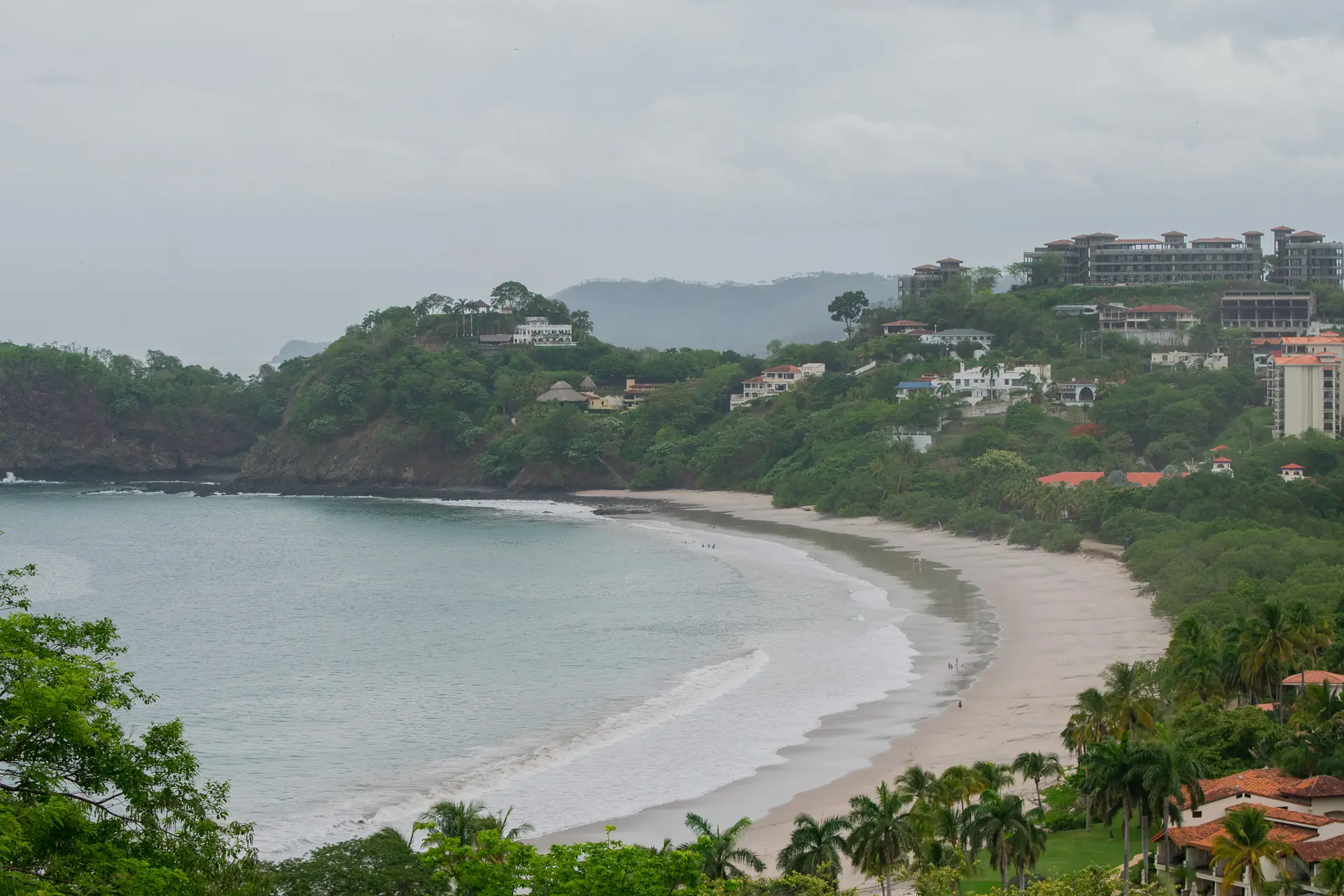 Curved white-sand bay with a hillside town at Playa Flamingo